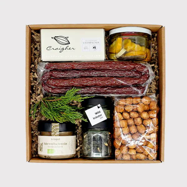 Geschenkbox „zünftig“ von Adam Geschenke mit Wurstspezialitäten, Schokolade, eingelegtem Gemüse, Gewürzen und herzhaften Knabbereien